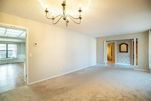 carpeted spare room featuring a textured ceiling and a chandelier