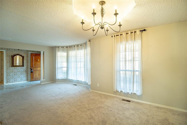 spare room featuring carpet floors, a textured ceiling, and a chandelier