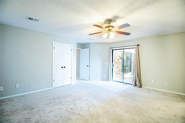 carpeted spare room featuring a textured ceiling and ceiling fan