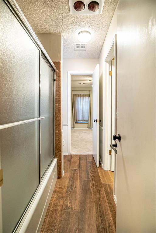 corridor featuring wood-type flooring and a textured ceiling