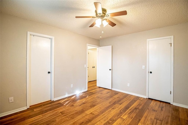 unfurnished bedroom featuring dark hardwood / wood-style floors, ceiling fan, and a textured ceiling