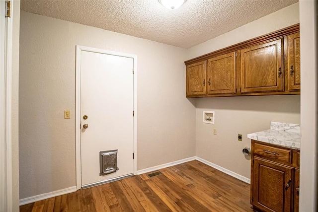 clothes washing area featuring cabinets, hookup for a washing machine, a textured ceiling, electric dryer hookup, and dark hardwood / wood-style floors