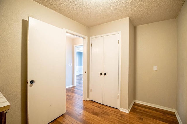 corridor featuring wood-type flooring and a textured ceiling