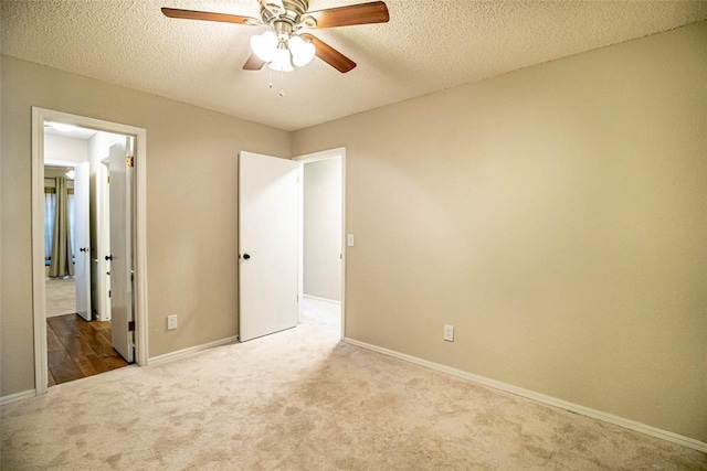 unfurnished bedroom featuring ceiling fan, light colored carpet, and a textured ceiling