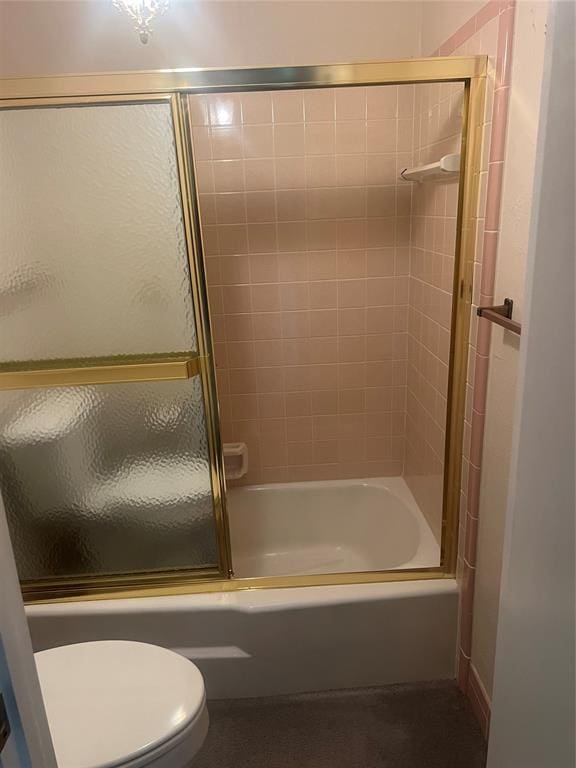 bathroom with toilet and shower / bath combination with glass door