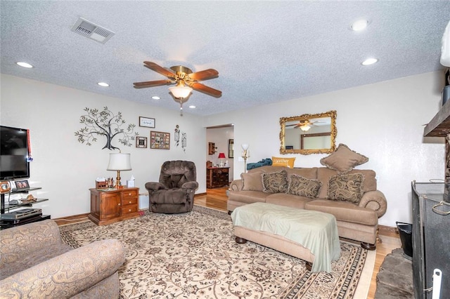 living room with a textured ceiling, light hardwood / wood-style flooring, and ceiling fan