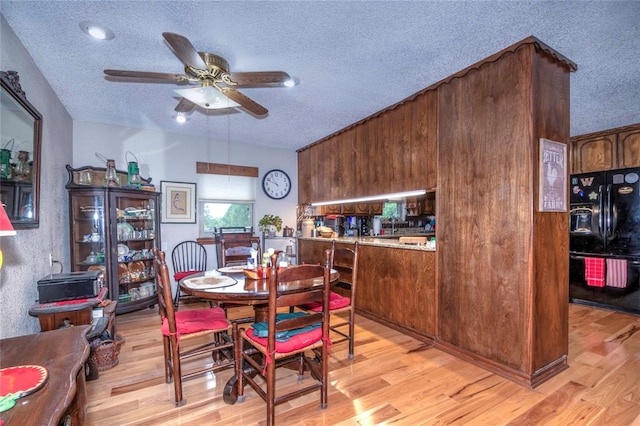 dining room featuring ceiling fan, light hardwood / wood-style flooring, and a textured ceiling