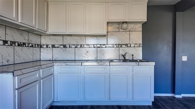 kitchen with backsplash, white cabinetry, dark wood-type flooring, and sink