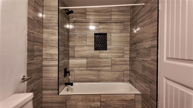 bathroom with tiled shower / bath combo and toilet