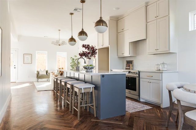 kitchen with pendant lighting, dark parquet floors, electric range, and a kitchen island with sink