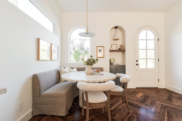 dining room with breakfast area, a healthy amount of sunlight, and dark parquet flooring