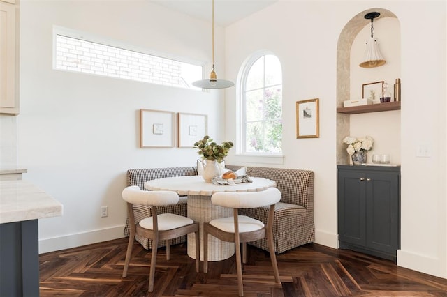 dining space featuring breakfast area and dark parquet floors