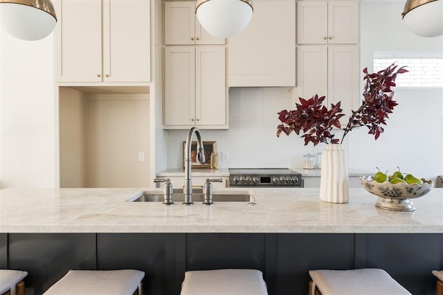 kitchen featuring a kitchen breakfast bar, stainless steel stove, light stone counters, and sink