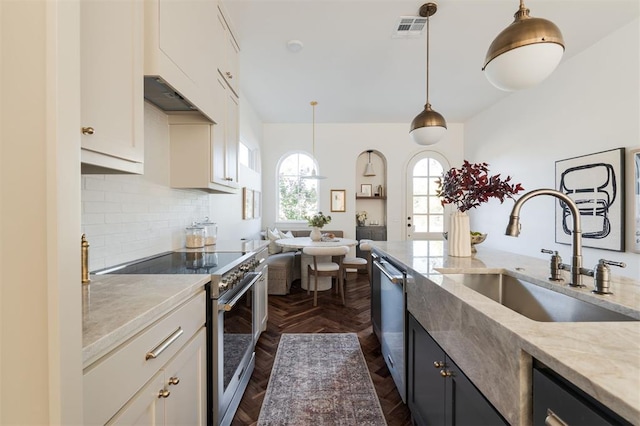 kitchen with sink, white cabinets, hanging light fixtures, and appliances with stainless steel finishes