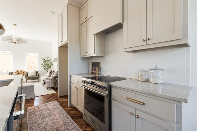 kitchen with decorative backsplash, light stone countertops, appliances with stainless steel finishes, decorative light fixtures, and a chandelier