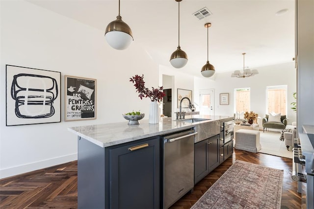 kitchen featuring sink, hanging light fixtures, light stone counters, a center island with sink, and appliances with stainless steel finishes