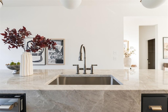 kitchen featuring light stone counters and sink