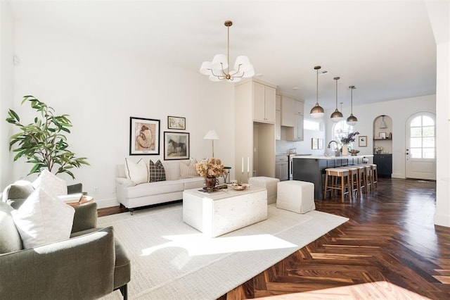 living room with parquet flooring, sink, and an inviting chandelier