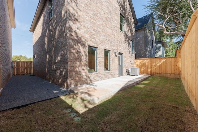 view of side of home featuring a lawn, cooling unit, and a patio area