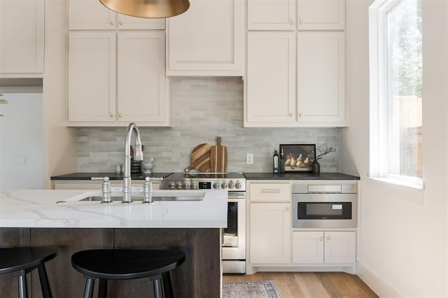 kitchen with light hardwood / wood-style floors, white cabinetry, and dark stone counters