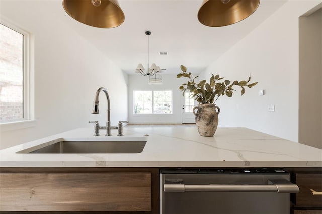 kitchen with pendant lighting, dishwasher, an inviting chandelier, sink, and light stone countertops