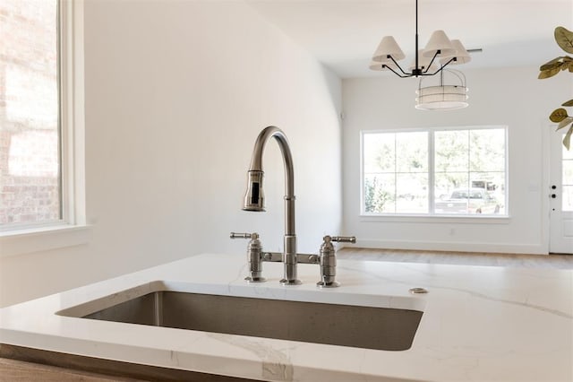 interior details with light stone countertops, sink, pendant lighting, and a notable chandelier