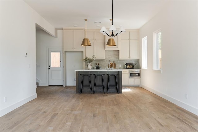 kitchen featuring tasteful backsplash, light hardwood / wood-style flooring, a center island, hanging light fixtures, and a breakfast bar area