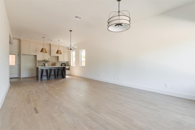 unfurnished living room featuring light hardwood / wood-style floors and a chandelier