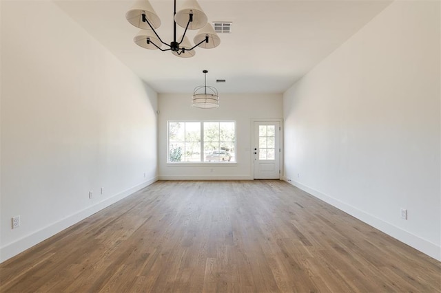 spare room with hardwood / wood-style floors and a notable chandelier