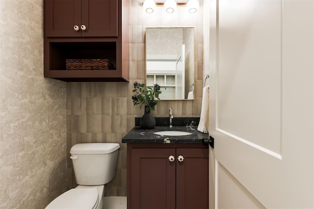 bathroom with vanity, toilet, and tile walls