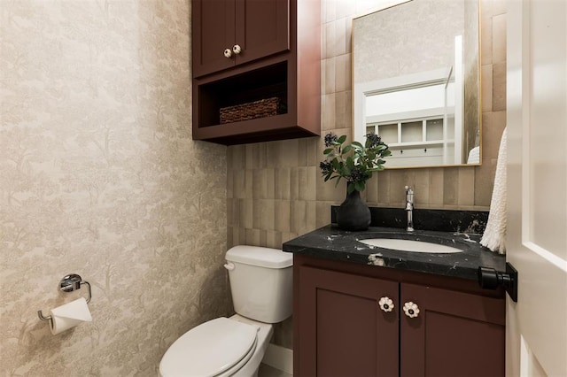 bathroom with vanity, toilet, and tile walls