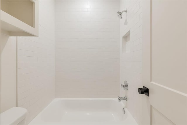 bathroom featuring toilet and tiled shower / bath