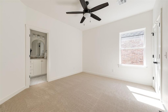 unfurnished bedroom featuring ensuite bathroom, sink, ceiling fan, and light carpet