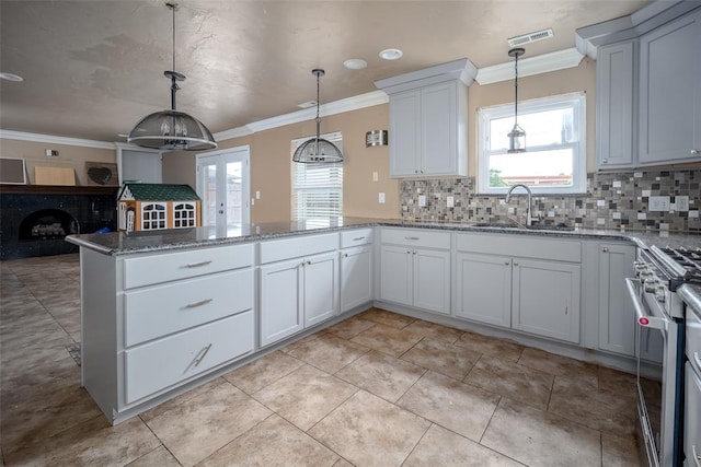 kitchen with white cabinetry, stainless steel range, sink, hanging light fixtures, and kitchen peninsula