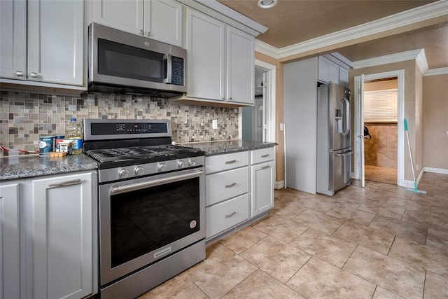 kitchen featuring decorative backsplash, appliances with stainless steel finishes, dark stone counters, crown molding, and white cabinets