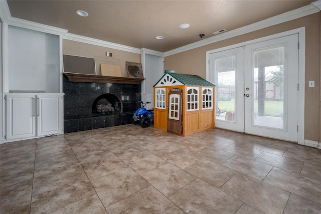 interior space featuring a tile fireplace, french doors, and ornamental molding