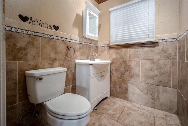 bathroom featuring vanity, toilet, and tile walls