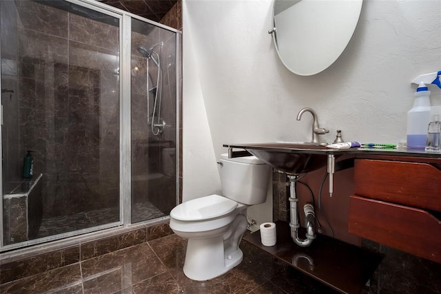 bathroom with toilet, a shower with shower door, and sink