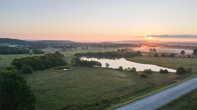 aerial view at dusk featuring a rural view and a water and mountain view