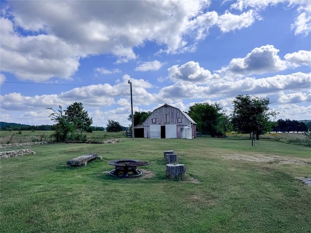 view of yard with an outbuilding, a rural view, and an outdoor fire pit