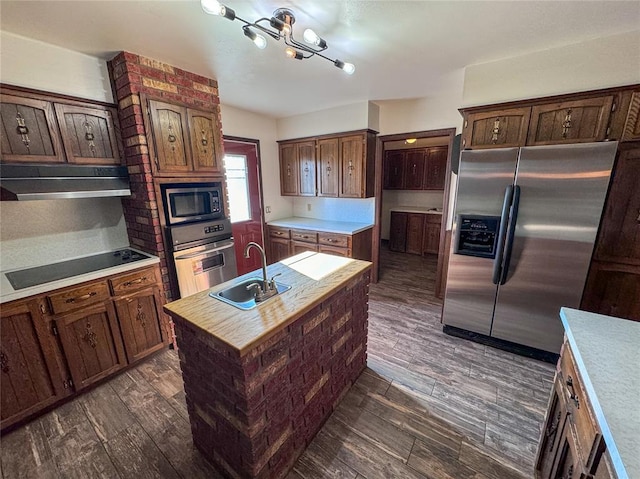 kitchen featuring dark hardwood / wood-style floors, sink, stainless steel appliances, and an island with sink