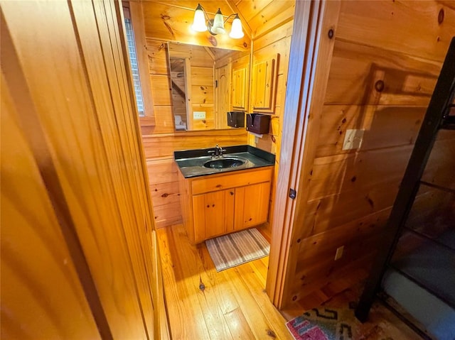 bathroom with hardwood / wood-style floors, vanity, and wood walls