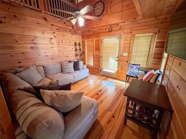 living room featuring light hardwood / wood-style floors, ceiling fan, and wood walls