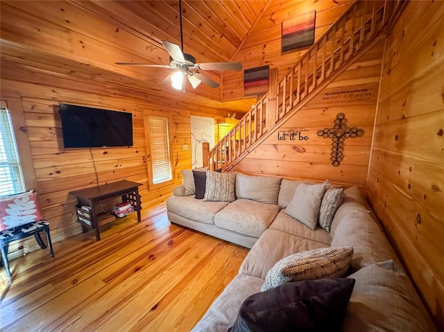 living room featuring wood walls, ceiling fan, wood-type flooring, and vaulted ceiling