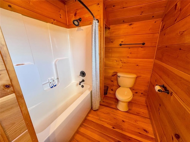 bathroom with hardwood / wood-style flooring, wood walls, toilet, and shower / tub combo