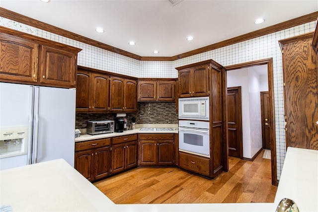 kitchen featuring backsplash, light wood-type flooring, white appliances, and crown molding