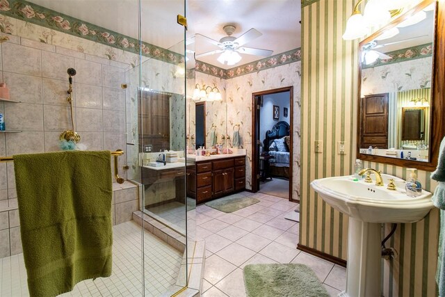 bathroom with tile patterned floors, ceiling fan, a shower with door, and dual sinks