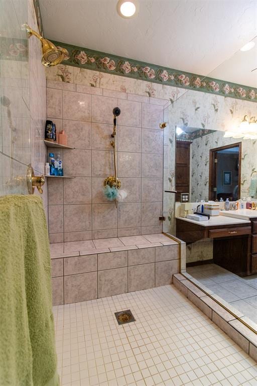 bathroom with tile patterned flooring, vanity, and tiled shower