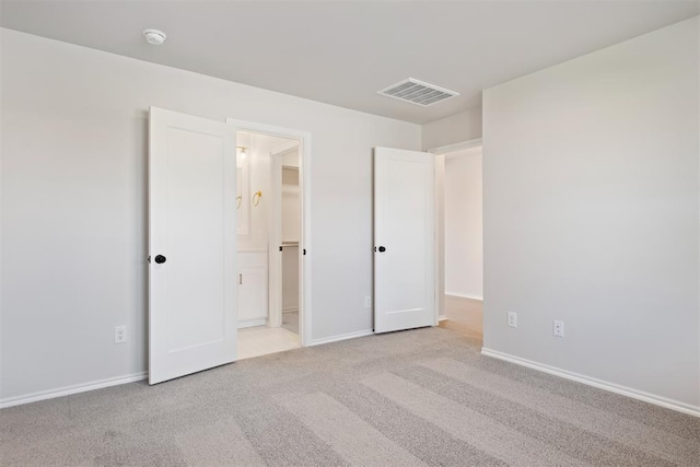 unfurnished bedroom featuring ensuite bathroom and light carpet