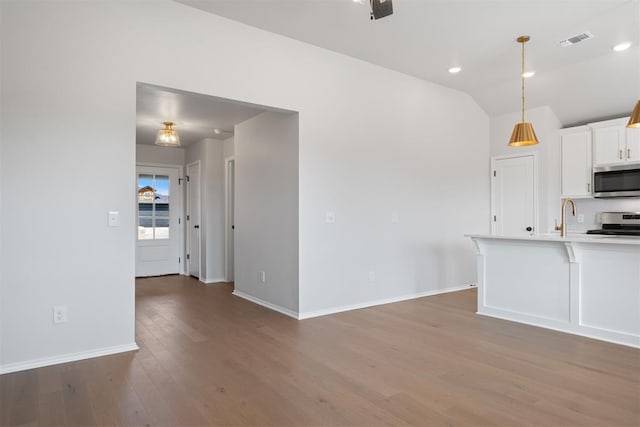 kitchen with white cabinets, hanging light fixtures, dark hardwood / wood-style floors, decorative backsplash, and stainless steel appliances